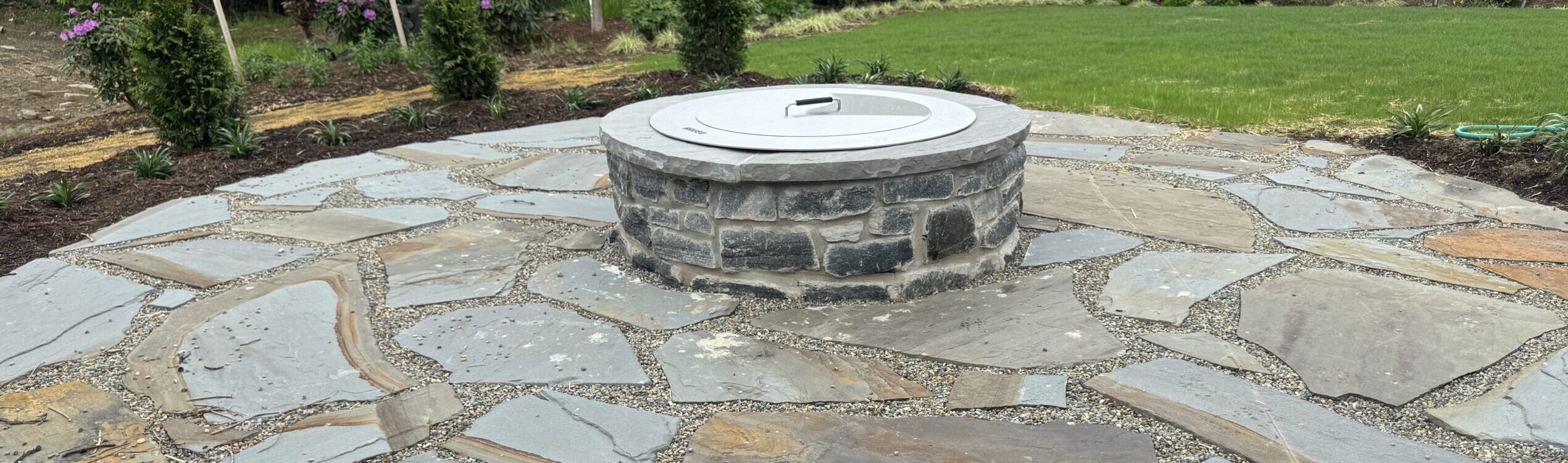 custom natural flagstone patio and seating area with a central fire pit.